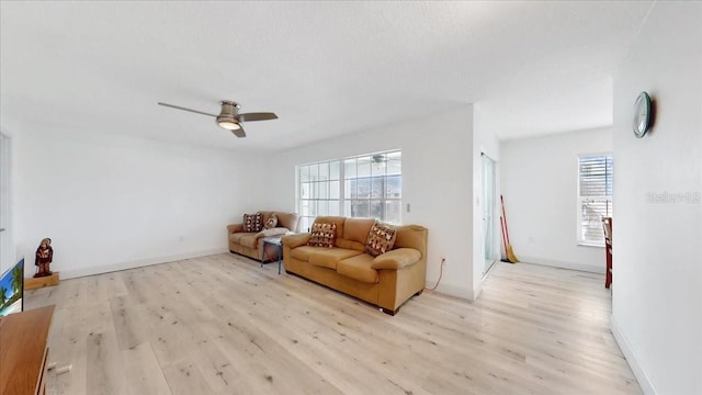 living room with light wood-type flooring, plenty of natural light, and ceiling fan