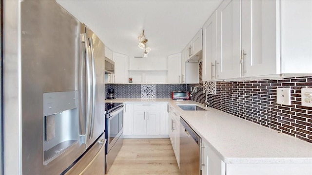 kitchen featuring white cabinetry, sink, stainless steel appliances, and light hardwood / wood-style floors