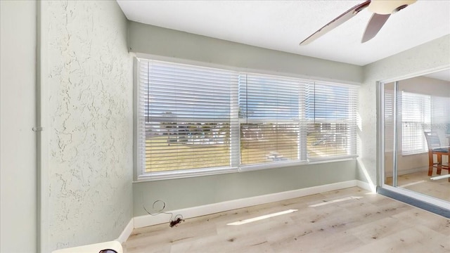 unfurnished room with light wood-type flooring, ceiling fan, and a healthy amount of sunlight