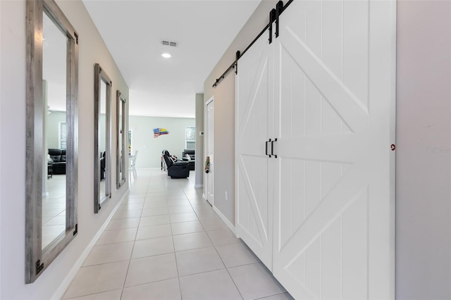 hallway with a barn door and light tile patterned floors