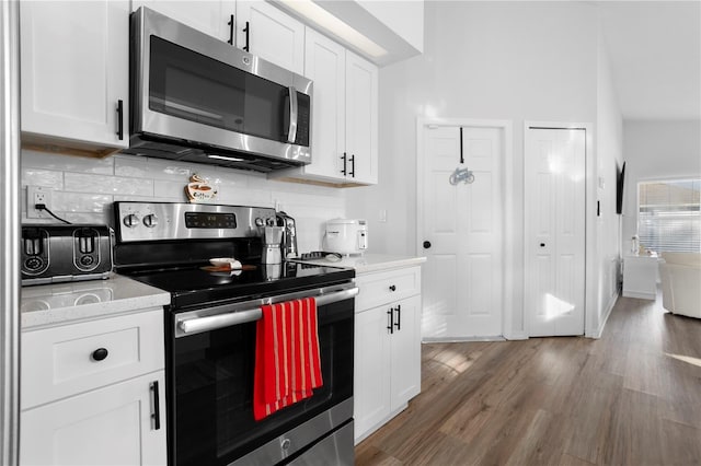 kitchen with white cabinets, dark hardwood / wood-style flooring, stainless steel appliances, and tasteful backsplash