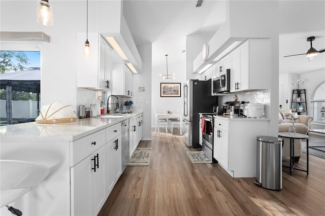 kitchen featuring sink, decorative backsplash, appliances with stainless steel finishes, decorative light fixtures, and white cabinetry