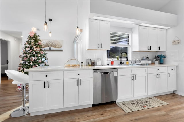 kitchen featuring white cabinetry, dishwasher, decorative light fixtures, and light wood-type flooring