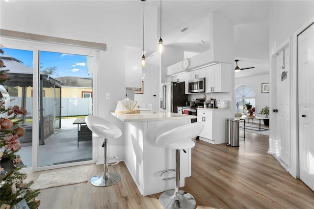 kitchen featuring a kitchen breakfast bar, white cabinets, pendant lighting, and appliances with stainless steel finishes