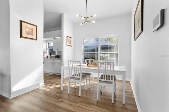 dining room featuring light wood-type flooring, a notable chandelier, and sink