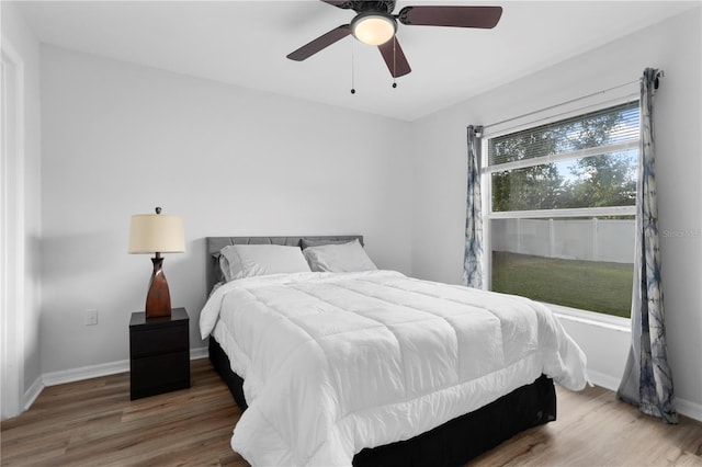 bedroom with multiple windows, wood-type flooring, and ceiling fan