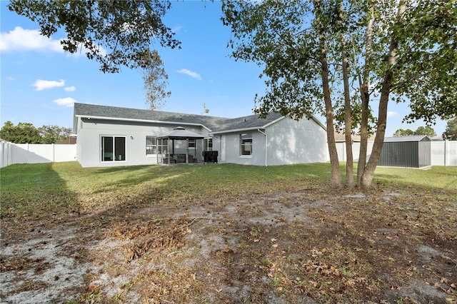 rear view of property with a gazebo and a yard