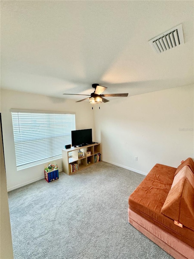 living area with a textured ceiling and ceiling fan