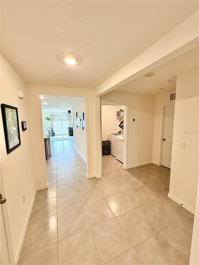 hall featuring washing machine and dryer, light tile patterned floors, and a textured ceiling