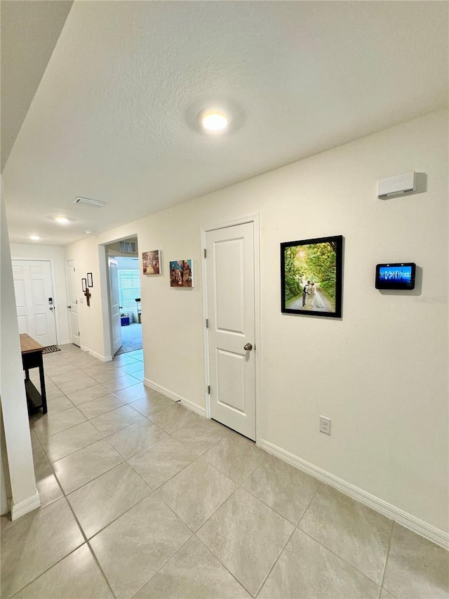 hall featuring light tile patterned floors and a textured ceiling