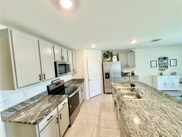 kitchen featuring sink, light tile patterned floors, gray cabinetry, stainless steel appliances, and a textured ceiling