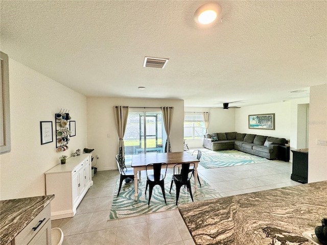 dining space with a textured ceiling and light tile patterned floors