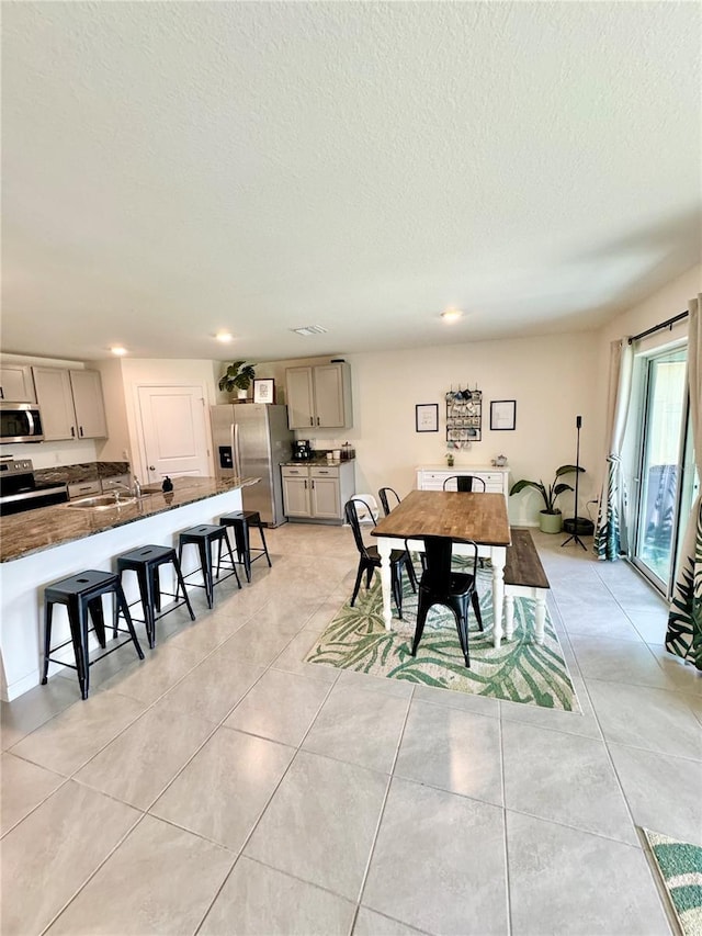 dining area with sink, a textured ceiling, and light tile patterned floors