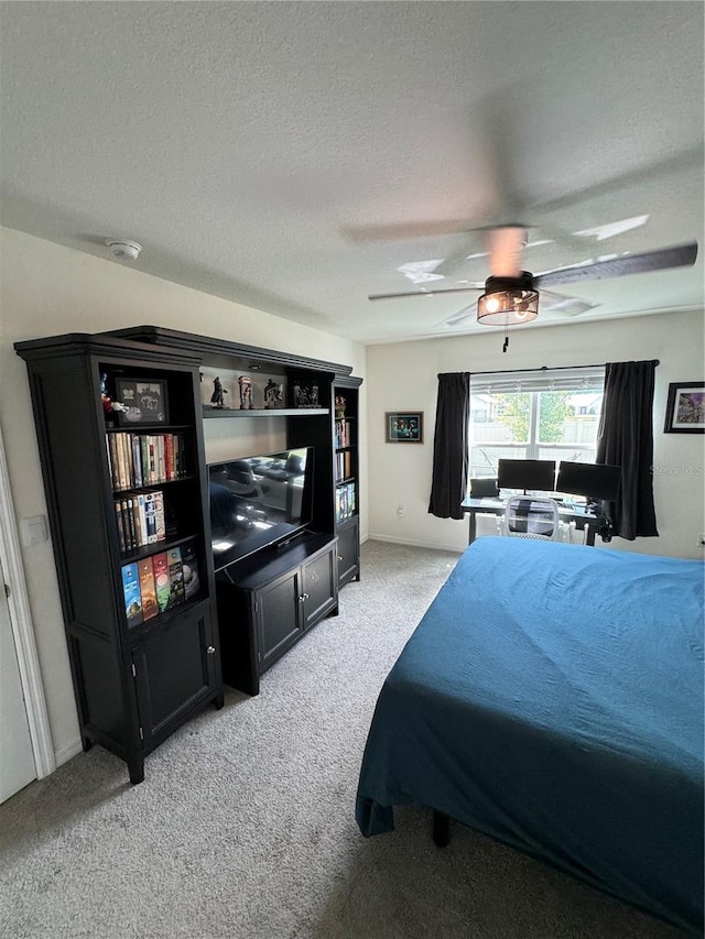 bedroom featuring ceiling fan, light colored carpet, and a textured ceiling