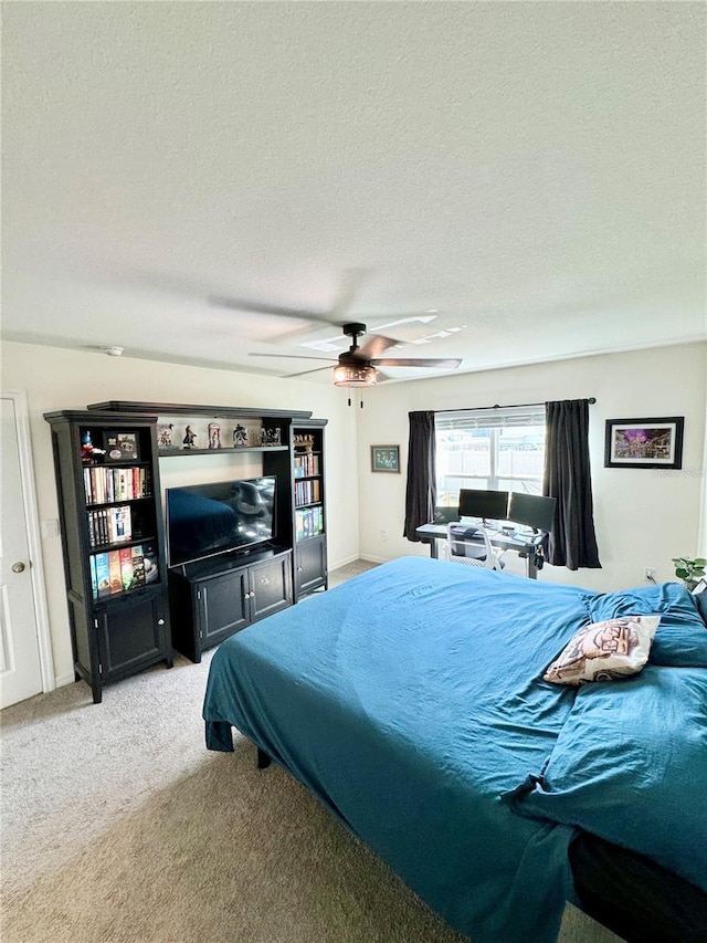 bedroom with ceiling fan, light carpet, and a textured ceiling