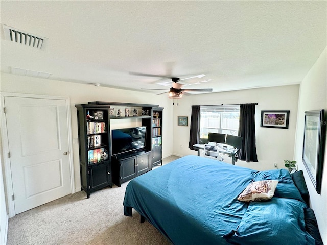 bedroom featuring ceiling fan, light carpet, and a textured ceiling