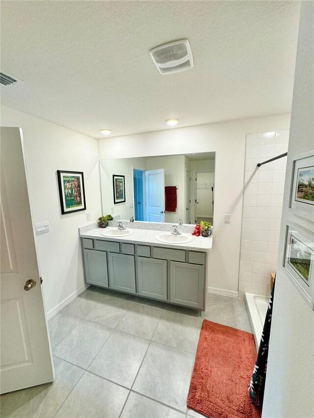 bathroom with vanity, tiled shower, tile patterned floors, and a textured ceiling