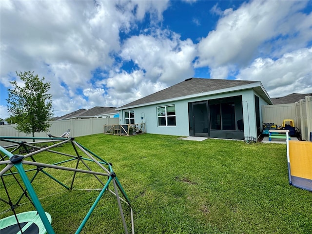 rear view of property with a yard and a playground