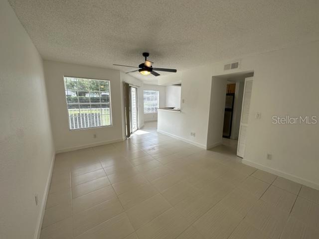 unfurnished room with ceiling fan and a textured ceiling