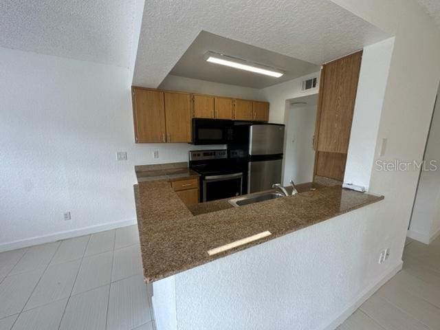 kitchen featuring stainless steel fridge, sink, a textured ceiling, and electric range oven