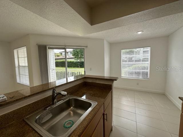 kitchen featuring a textured ceiling, light tile patterned floors, and sink