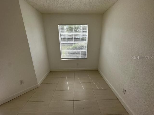 unfurnished room with light tile patterned floors and a textured ceiling