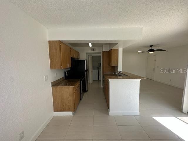 kitchen with kitchen peninsula, a textured ceiling, ceiling fan, black electric range, and light tile patterned flooring