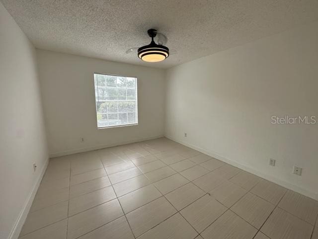 spare room featuring light tile patterned flooring and a textured ceiling