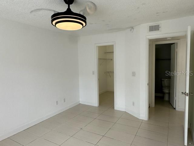 unfurnished bedroom with light tile patterned floors, a textured ceiling, a spacious closet, and a closet