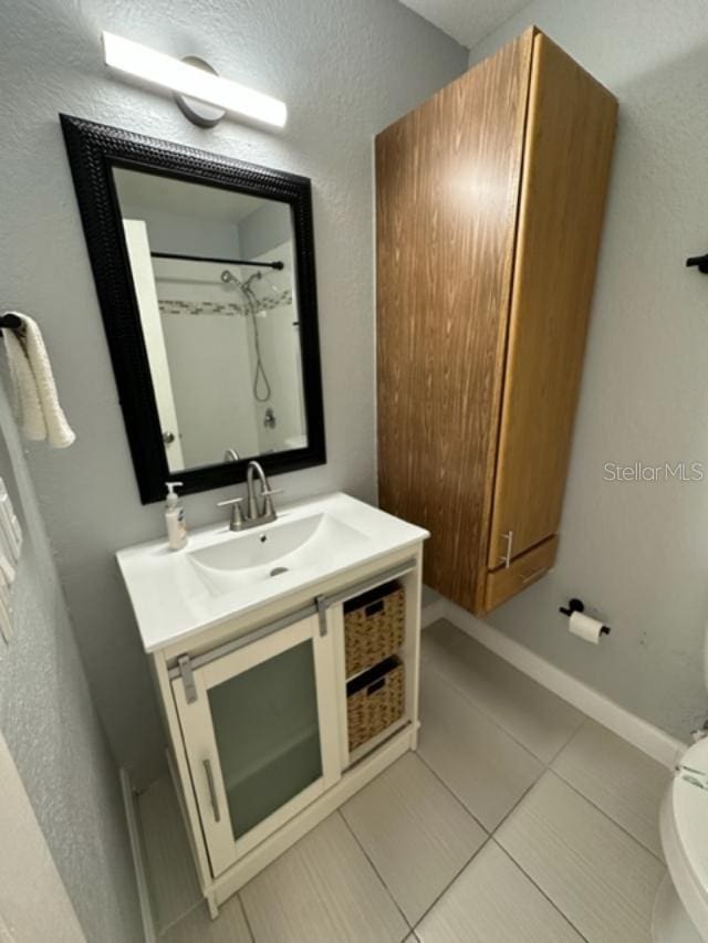 bathroom featuring tile patterned flooring, a shower, vanity, and toilet