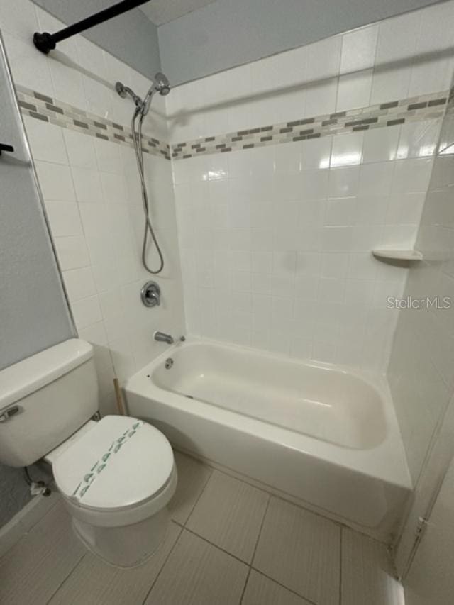 bathroom with tile patterned floors, tiled shower / bath, and toilet