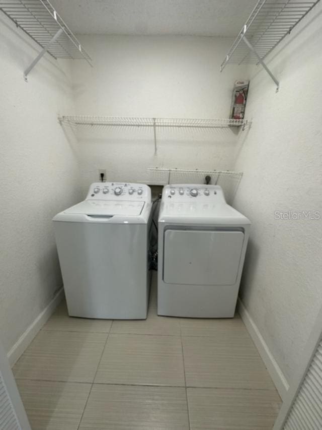 washroom featuring washing machine and clothes dryer and light tile patterned floors