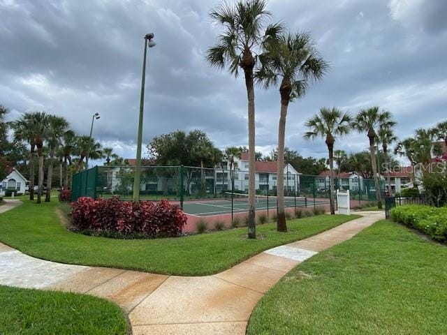 view of property's community with a lawn and tennis court