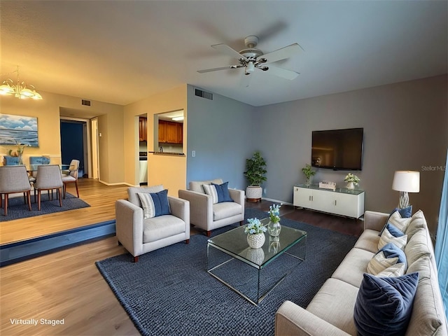 living room with hardwood / wood-style floors and ceiling fan with notable chandelier