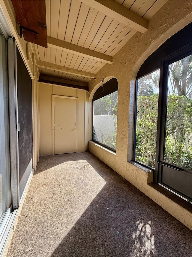 unfurnished sunroom featuring beamed ceiling