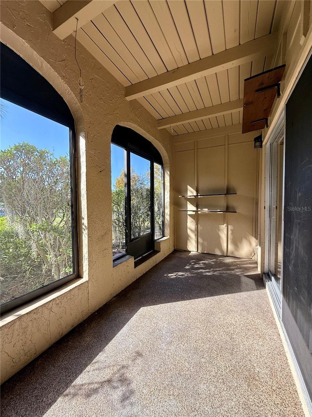 unfurnished sunroom featuring beam ceiling