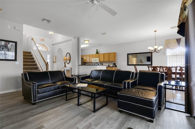 living room with ceiling fan with notable chandelier and light hardwood / wood-style floors