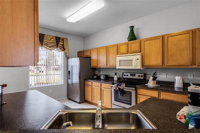 kitchen with light tile patterned floors, a textured ceiling, stainless steel appliances, and sink