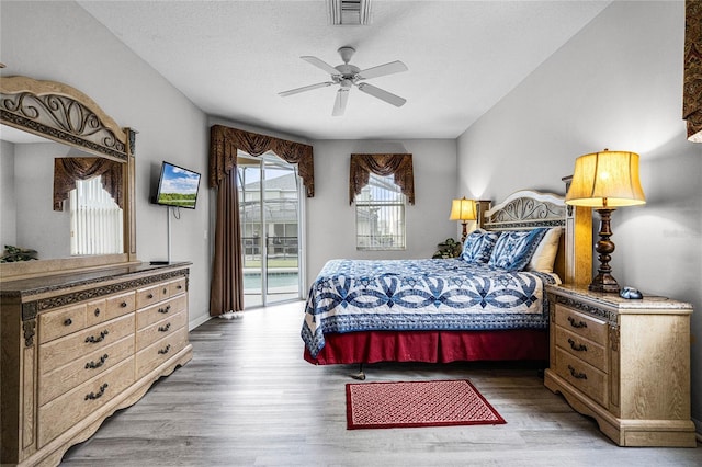 bedroom featuring access to exterior, a textured ceiling, light hardwood / wood-style flooring, and ceiling fan