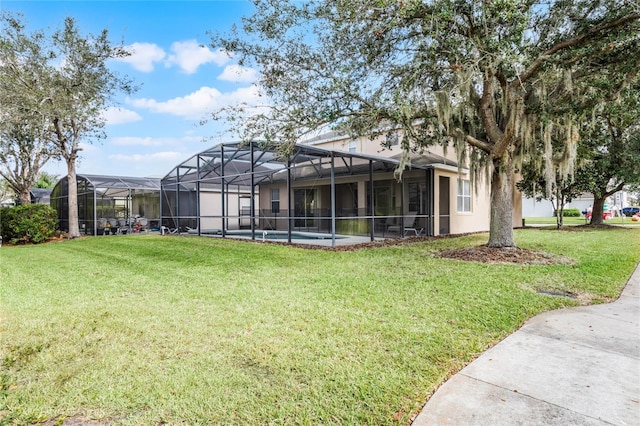 rear view of property with glass enclosure and a yard