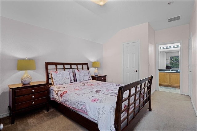 bedroom featuring ensuite bath, carpet, and vaulted ceiling