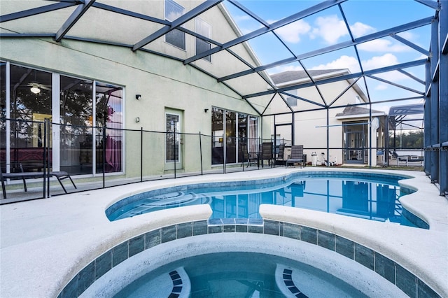 view of pool featuring glass enclosure, an in ground hot tub, and a patio