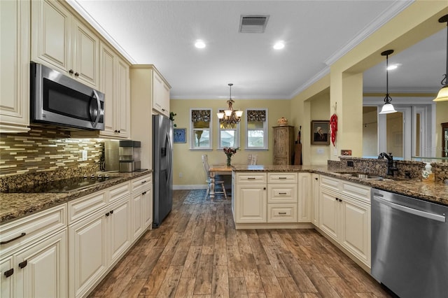 kitchen featuring hardwood / wood-style floors, appliances with stainless steel finishes, hanging light fixtures, and sink