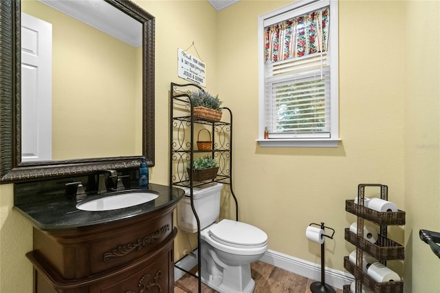 bathroom with hardwood / wood-style flooring, vanity, toilet, and crown molding