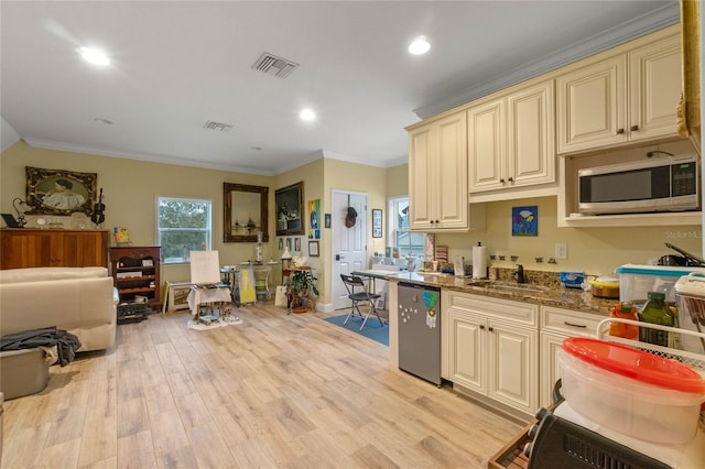 kitchen with sink, dark stone countertops, light hardwood / wood-style floors, cream cabinetry, and appliances with stainless steel finishes