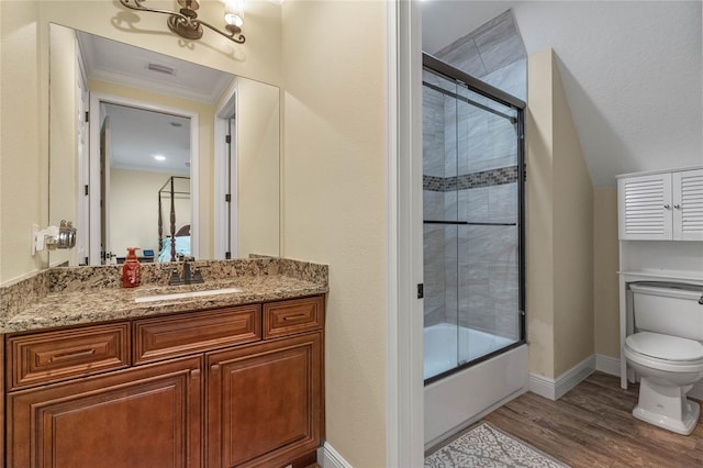 full bathroom with hardwood / wood-style floors, vanity, bath / shower combo with glass door, toilet, and ornamental molding