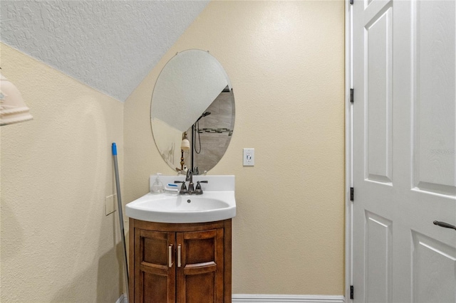 bathroom featuring vanity, lofted ceiling, and a textured ceiling