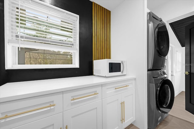 laundry area featuring cabinets and stacked washer and clothes dryer