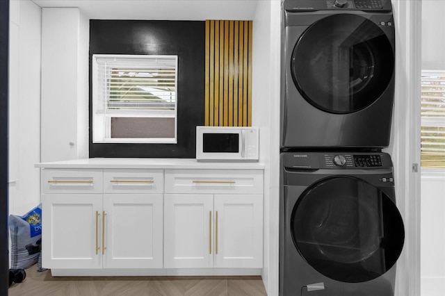 clothes washing area featuring stacked washer / dryer and light parquet floors