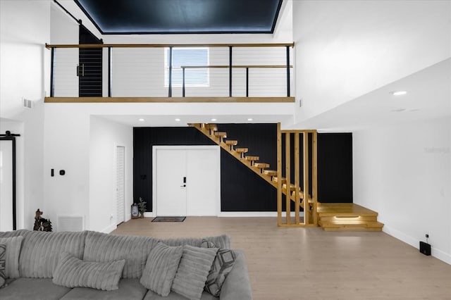 living room featuring a towering ceiling and light wood-type flooring